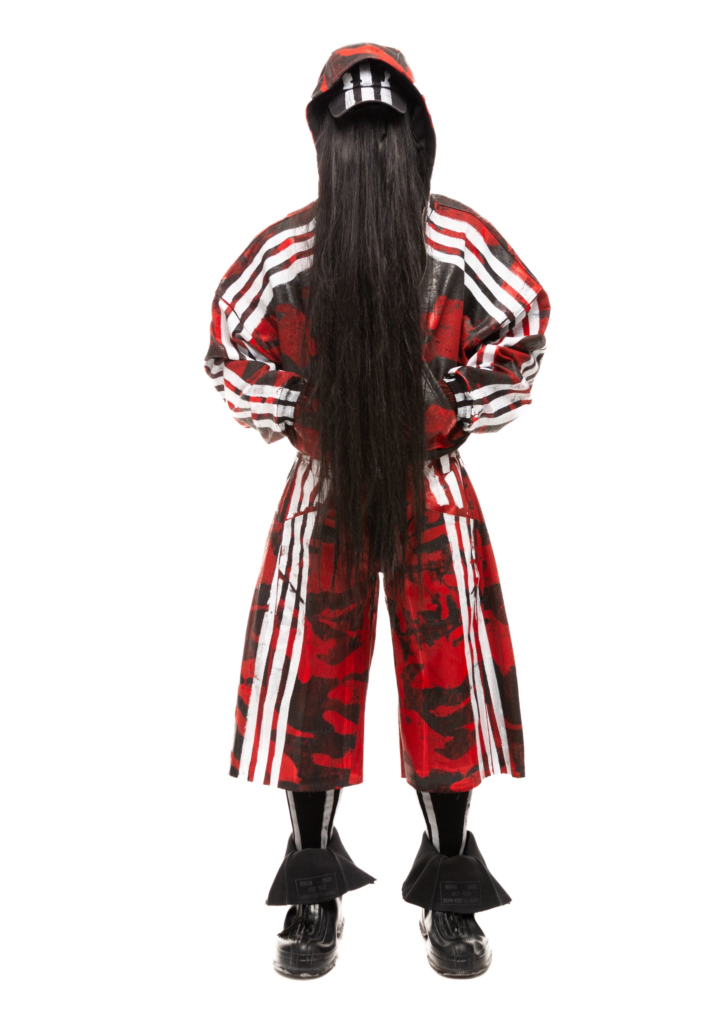 Model wearing red waxed denim shorts with white stripes and camouflage print, front view.