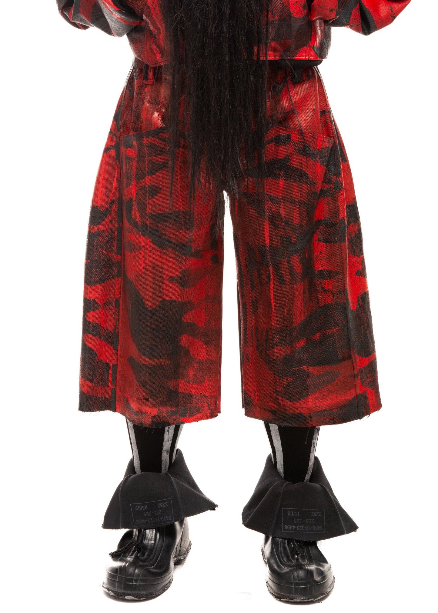 Close-up front detail of waxed red denim with black camo print and raw hem