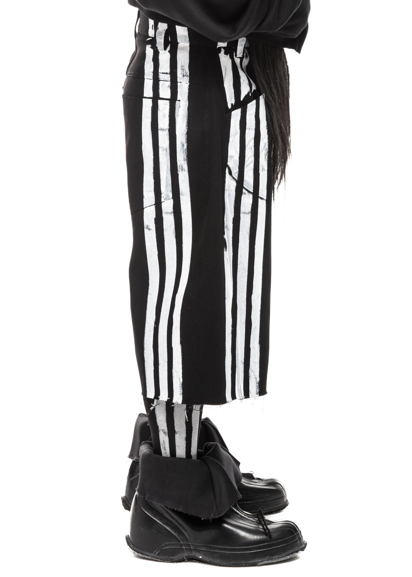 Side angle of striped black denim shorts showing raw edge texture and oversized silhouette.