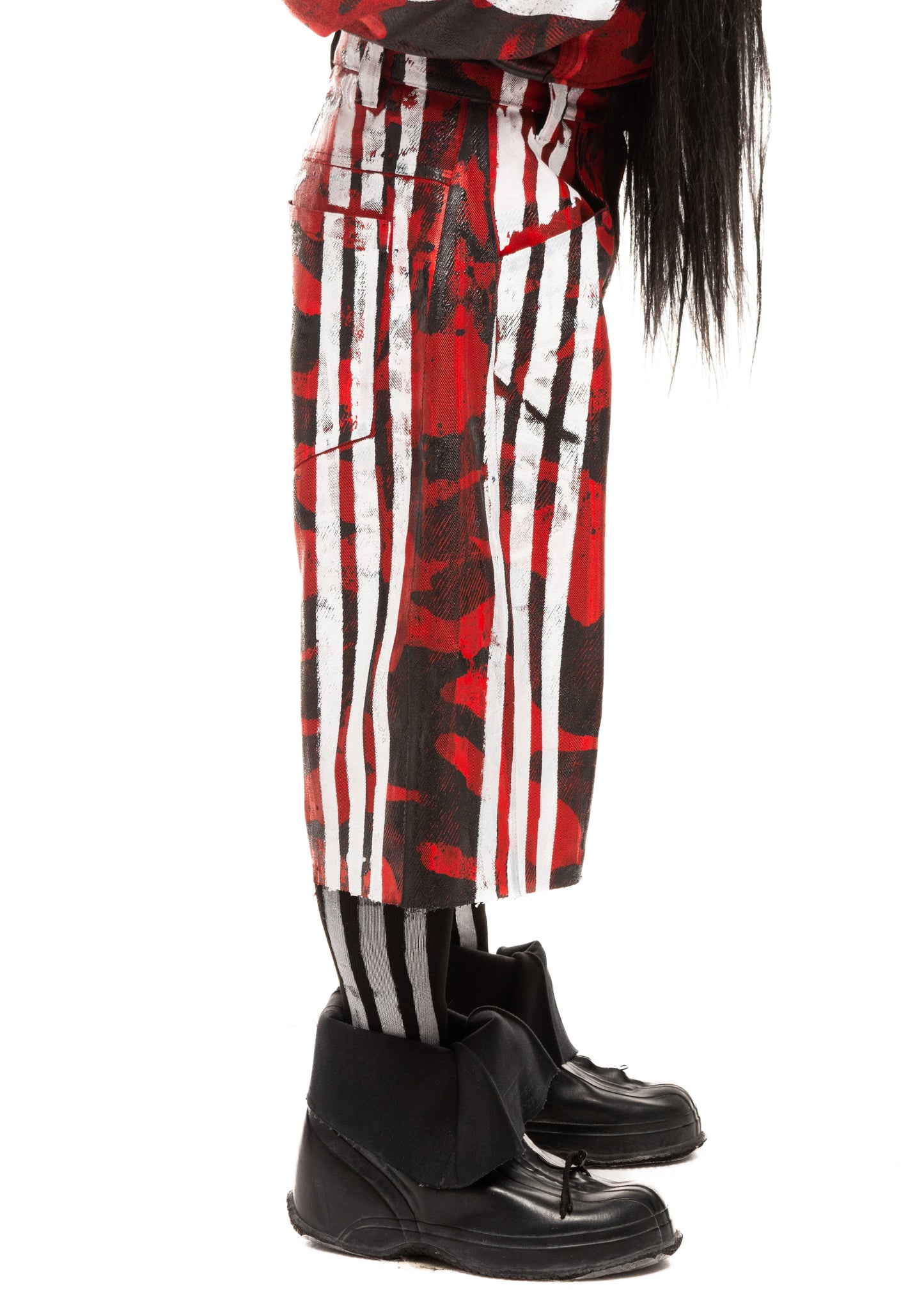 Side close-up of waxed red denim shorts with white printed stripes and bold camo pattern, highlighting texture and cut.