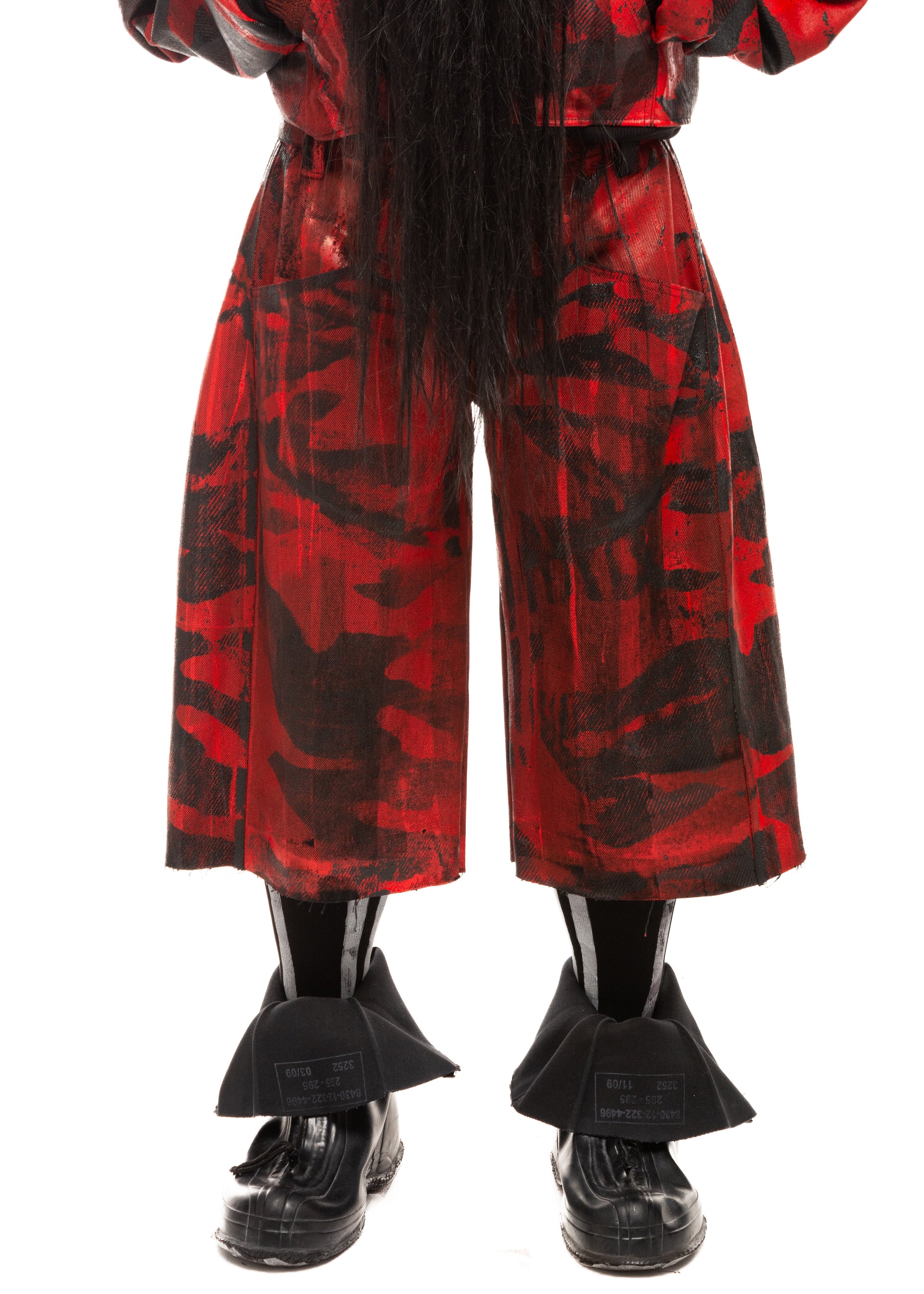 Close-up front detail of waxed red denim with black camo print and raw hem